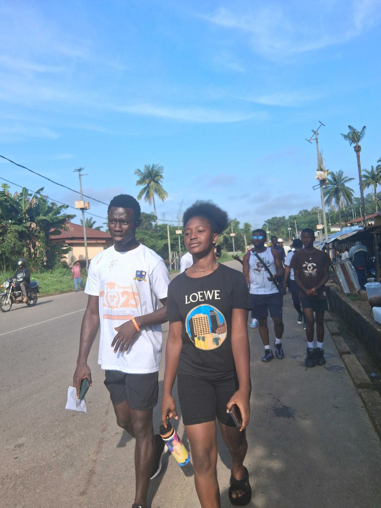 Two people walking side by side down a neighborhood street, smiling